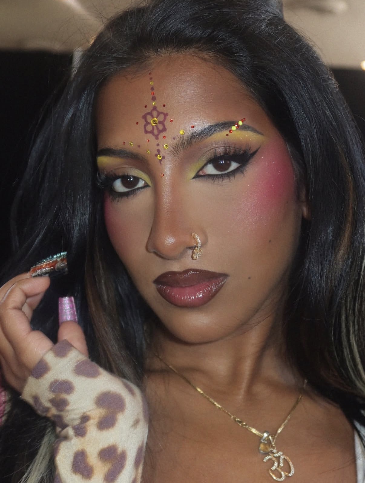 Close up portrait of Lara Raj from Katseye with a bold makeup look featuring a graphic flower design bindi adorned with crystals